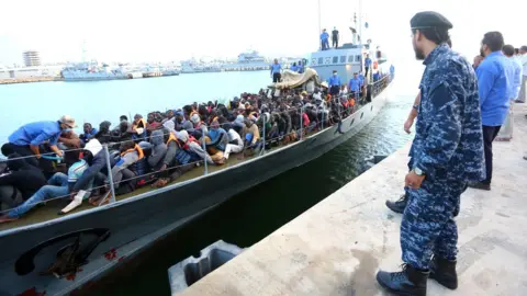 Getty Images Migrants rescued by the Libyan coastguard in the Mediterranean off the Libyan coast arrive at a naval base in the capital, Tripoli, on 26 May 2017