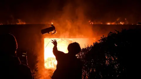 AFP A protester throws a fire extinguisher into a burning building overnight in Minneapolis