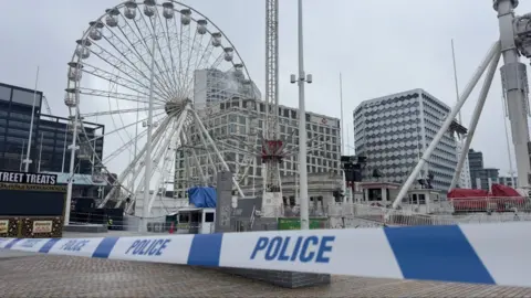 BBC Blue constabulary  portion    successful  the foreground, down  which the deserted City Star Flyer thrust   is visible, arsenic  good   arsenic  a ferris instrumentality    and bureau   buildings.