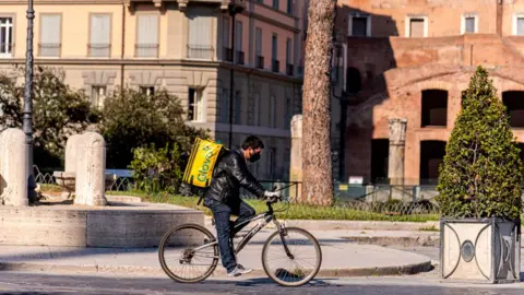 Getty Images A food delivery man rides his bicycle in Rome