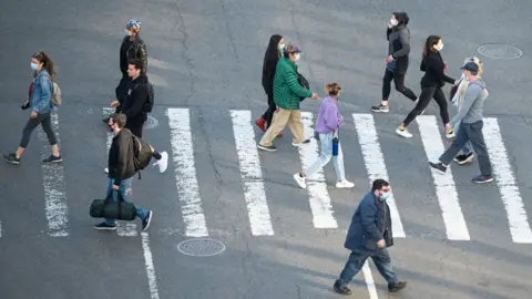 Getty Images people in masks crossing road