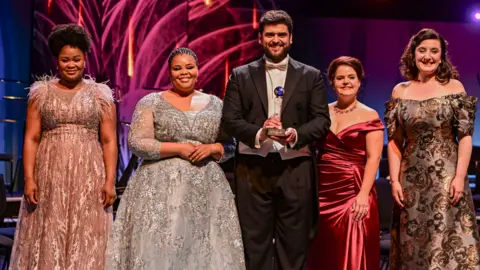 Finalists standing in a line with the prize held by winner Adolfo Corrado