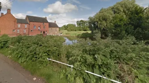 River flowing past trees, hedges and houses