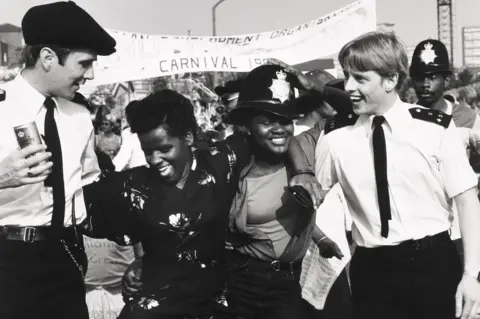 Sydney Orleans Harding / Museum of London Two uniformed policemen dancing with two carnival goers at the Notting Hill Carnival, 1980s