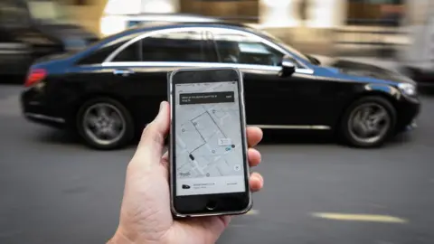 Getty Images Uber app on a smartphone in front of a car