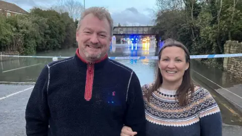 A couple standing in front of a flooded road