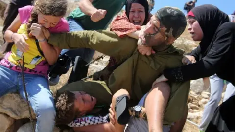 AFP Ahed Tamimi (left) bites an Israeli soldier trying to detain her brother (28/08/15)