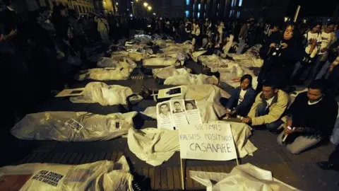 AFP People demonstrate by covering themselves with sheets pretending they are false positive victims, during a protest against the false positives, massacres and forced disappearances by Colombian authorities on March 6, 2009, in Bogota