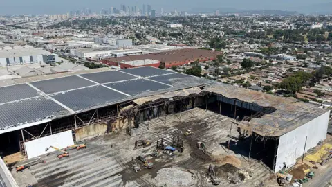Getty Images An aerial view of workers cleaning up the burnt out remains of the facility, with built-up LA in the background