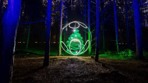 Kevin Jay Light painting of Christmas tree bauble among the trees in Thetford Forest, Norfolk
