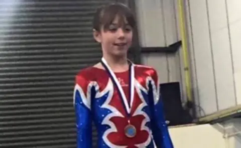 Family photo Chelsea Mooney wearing a gymnastics costume and medal