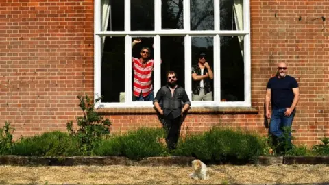 Reuters Band members pose in a garden as they isolate together with their families and pets in a rented luxury estate