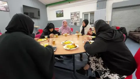 Women eat food at the Bangladeshi Youth Organisation
