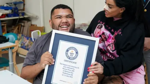 PA Media Katie Price and Harvey Price holding his Guinness World Record certificate