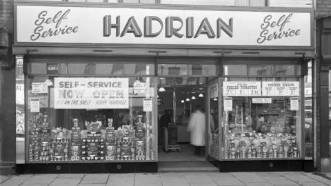 Newcastle Local Studies Library/Tyne Bridge A black and white view of a shop front with lots of signs offering self-service