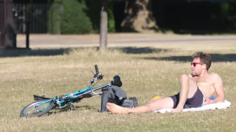 PA Media Man lying in the sun