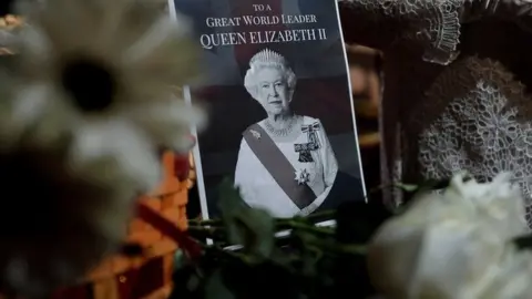 A note and a bouquet of flowers are pictured next to a wax model of Queen Elizabeth II at a wax museum in Shah Alam, Malaysia September 9, 2022.