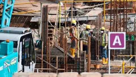 Getty Images Migrant workers work at a construction site in Singapore on August 20, 2020.