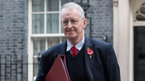 Getty Images Benn is holding red folder and wearing a poppy on his jacket. He's outside ten Downing St.