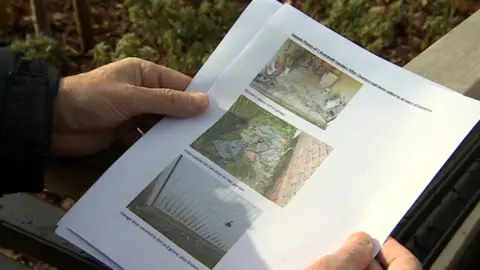 Colin holding photographs of their former property