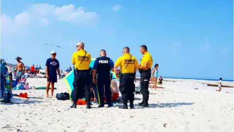@insert4coins/Instagram Police on beach surrounding injured woman