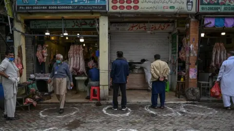 Getty Images Customers stand in circles on ground, as part of social distancing measures, outside shops in Islamabad