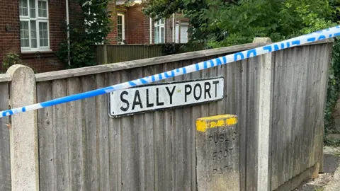 BBC/Aruna Iyengar Police tape by the road sign 'Sally Port'