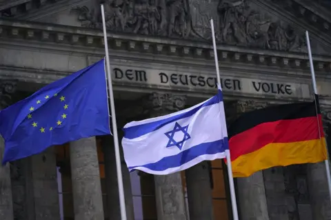 Clemens Bilan / EPA Flags of European Union, Israel and Germany are flown at half mast in Berlin to mark Holocaust Memorial Day