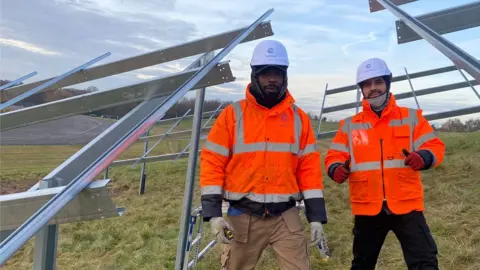 Moulton College Two men in orange hi-viz standing in a PV panel mounting frame