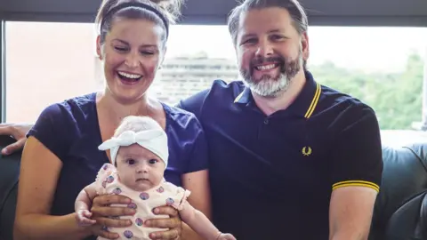 Carly McCrossin Carly (left) and her husband (right) with their daughter, Ailish