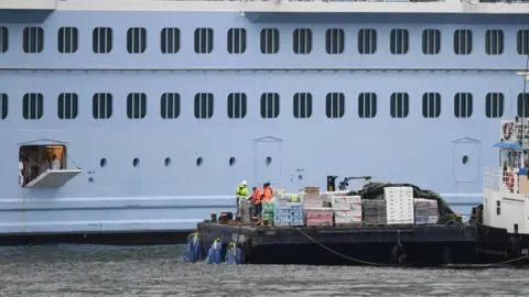 Getty Images hatch opened on side of cruise ship with supply tug alongside