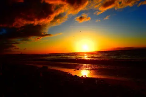 Matthew Jackson Orange/yellow sunset at a dark beach scene.