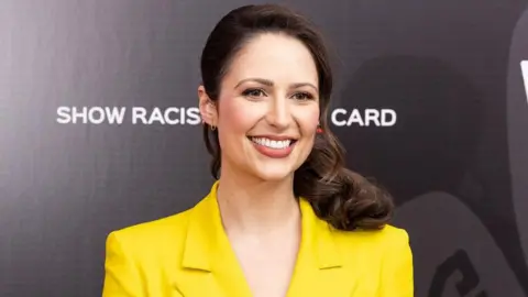 Getty Images  Nicola Thorp, wearing a yellow blazer, poses on the red carpet