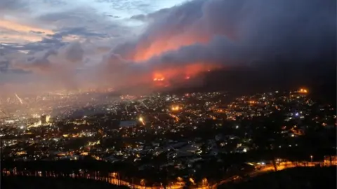 Reuters Flames are seen close to the city fanned by strong winds after a bushfire broke out on the slopes of Table Mountain in Cape Town, South Africa, April 19, 2021