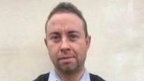 NON-POL Damon Sharp, a white man with brown hair, looks at the camera.