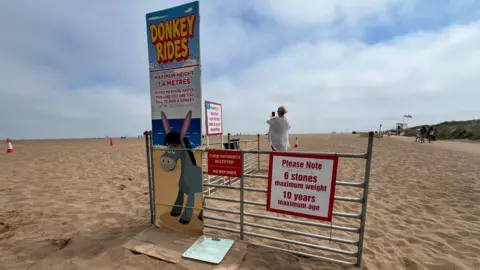 Kevin Shoesmith/BBC A set of scales by the donkey rides sign at Skegness beach