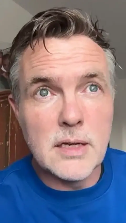 A man with grey hair and a blue tshirt.
