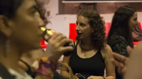 Megan Janetsky Isabel Pérez (centre, in focus) at an event