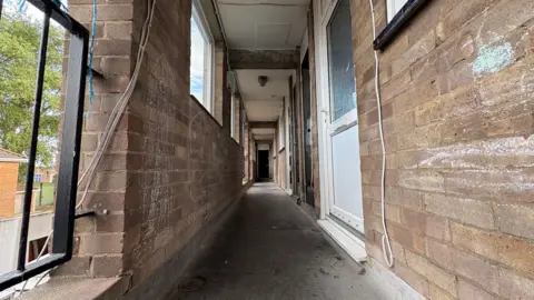 Martin Giles/BBC A view of a corridor in the block of council homes. Children have drawn on the brick walls in chalk.