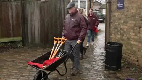 A Royal Park volunteer pushes a wheelbarrow