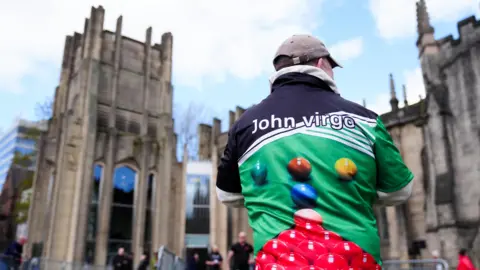 A man wearing a shirt with a snooker table and balls printed on stood outside Sheffield Cathedral.