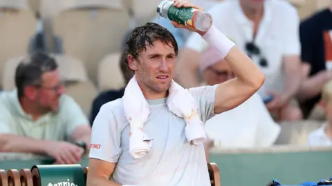 Casper Ruud pours water over his head during a change of ends