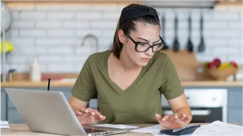 Getty Images Woman looks at bills