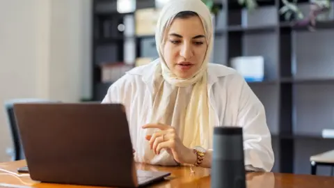 Getty Images Woman using a smart speaker at work