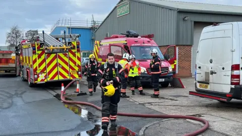 Steve Hubbard/BBC Fire fighters and appliances outside industrial unit in Eaton Socon