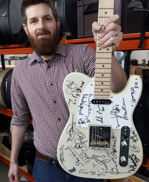 Gardiner Houlgate Auctioneer Luke Hobbs with the guitar