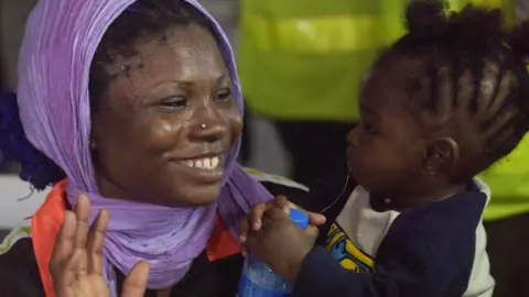 AFP A woman plays with a child during the screening of 150 migrants brought home from Libya at the Murtala Mohammed International Airport in Lagos, Nigeria - Tuesday 5 December 2017