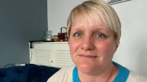 Andrew Turner/BBC Becky sitting on the sofa in her sitting room