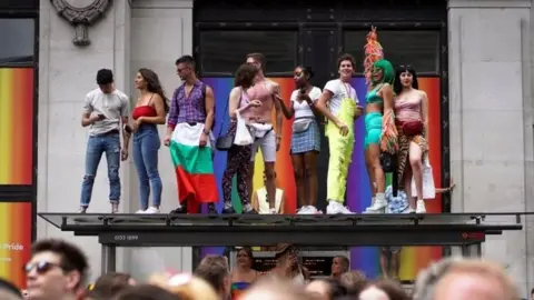 Reuters Revellers standing on a bus stop roof