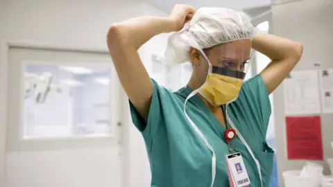 Getty Images Stock image of a nurse putting on a face covering